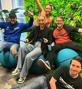 Colleagues sat on ball seats in front of office living wall