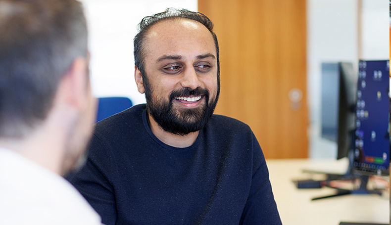 Two male colleagues chatting at a computer desk