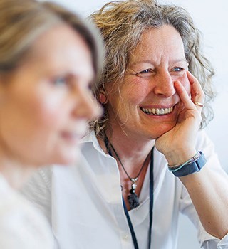 Two female colleagues chatting & smiling in the office