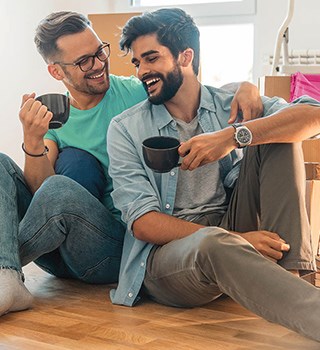 Two men laughing while drinking a coffee