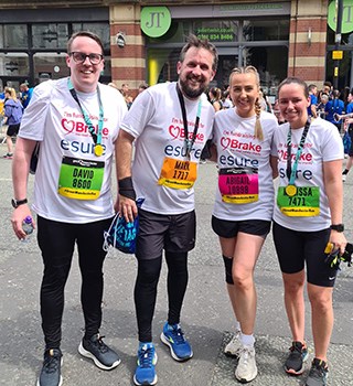 Four colleagues with running gear & medals from a charity race