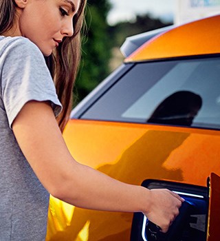 Woman plugging in charger to electric car