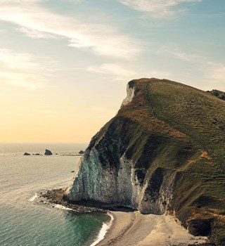 Coastal scene showing a cliff on the right & the sea on the left